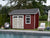 Charming red wooden shed by the pool with double doors, perfect for storing outdoor furniture and pool accessories
