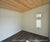Finished interior of a studio shed with wood ceiling, white walls, and a double-pane window for natural light.