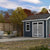 Small gray storage shed with patio furniture in a backyard setting