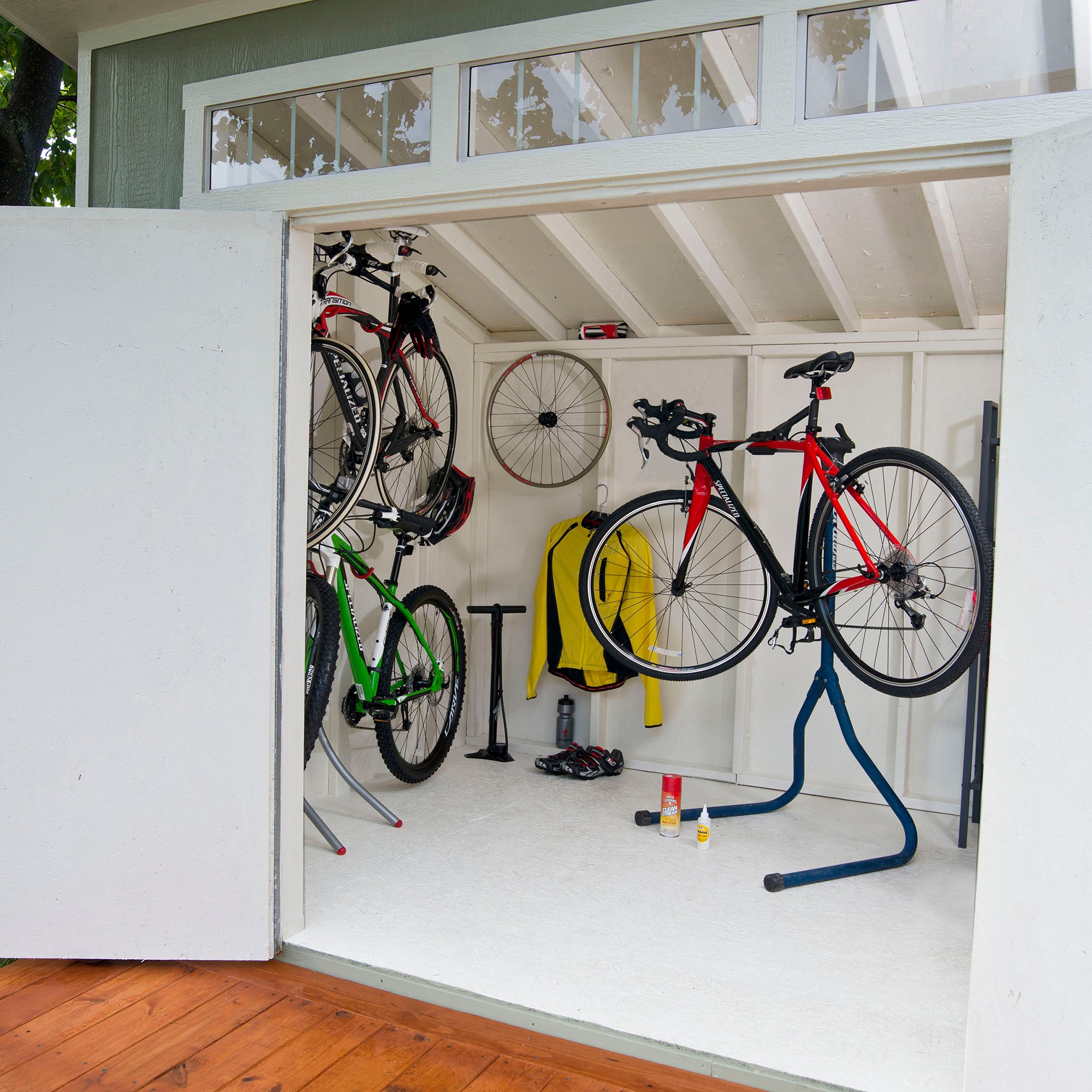 Modern shed converted into a bike workshop with hanging bicycles, storage racks, and organized cycling gear.