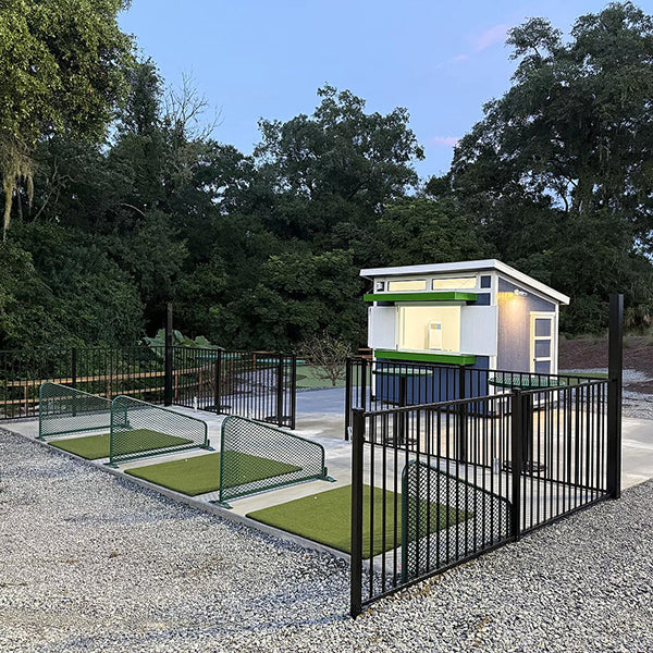 Small shed with a green with golf tee for driving practice and black fence